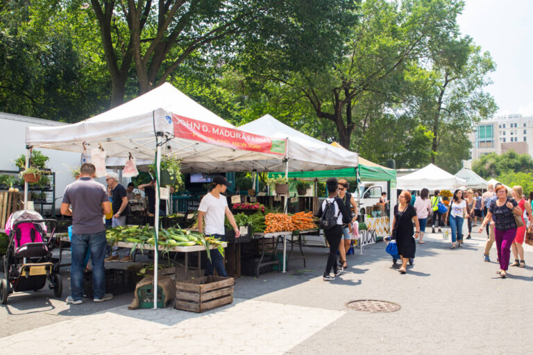 New York City, New York, USA - July 16, 2018: Shoppers buying fruit on display at the Union Square Greenmarket farmers market in Manhattan.