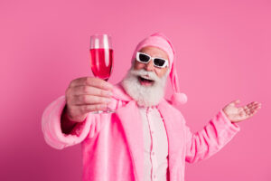 Portrait of excited elderly man raise champagne glass tell toast wear bathrobe isolated on pink color background.
