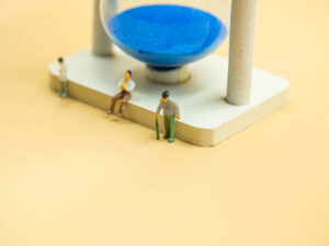 Closeup of sand glass and miniature figure of adolescence, adult and elder with blurry golden color background for life stages and time concept and idea.