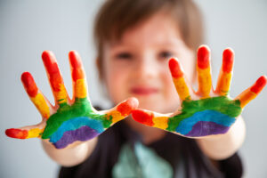 Cute little girl showing her hands with rainbow painted on them