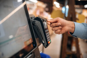 Wireless transfer. Close up view of man customer that is paying for products by credit card in grocery store.