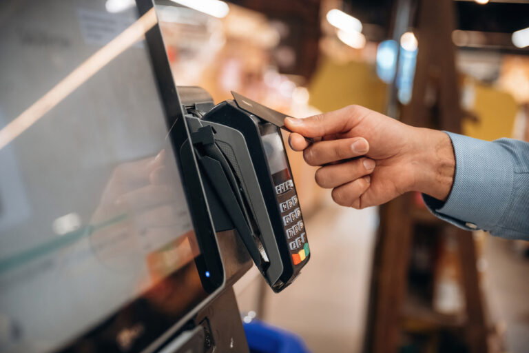 Wireless transfer. Close up view of man customer that is paying for products by credit card in grocery store.