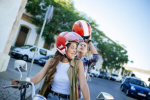 Happy young couple riding motorbike in urban area on summer day