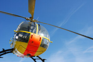 yellow and orange rescue helicopter, low angle view against blue sky