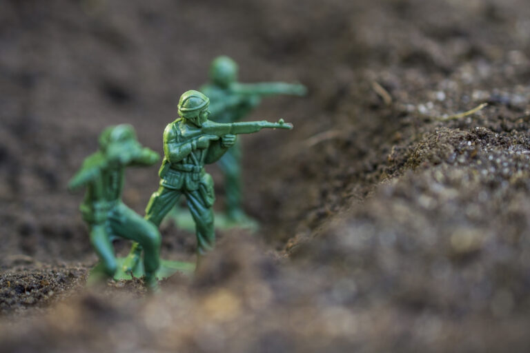 Action figures close-up. Toy soldiers in a mud trench.